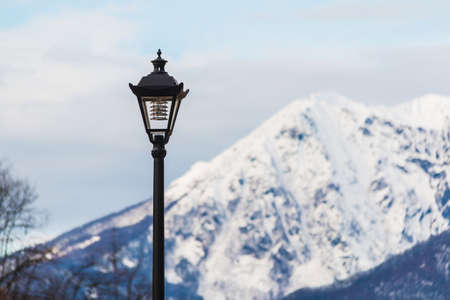 Streetlight on the background of mountain covered with snow in winter day closeup, Krasnaya Polyana,...