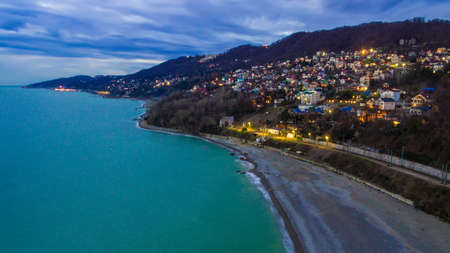 Drone view of the seaside with the illuminated district of the city of Sochi at twilight, Russiaの写真素材