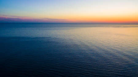 Drone view of a wide sea surface and the horizon at sunset