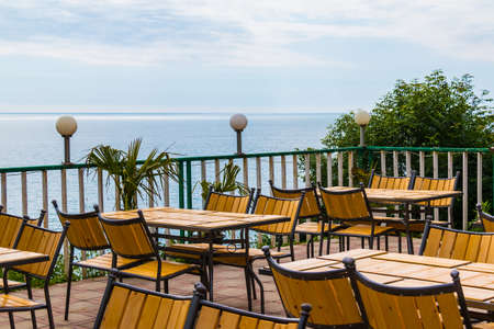 Terrace with wooden tables and chairs with sea view in sunny summer dayの写真素材