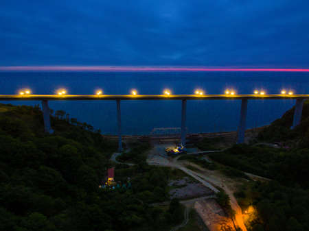 Drone view of the illuminated Zubova Schel viaduct between mountainsides with forest on the...