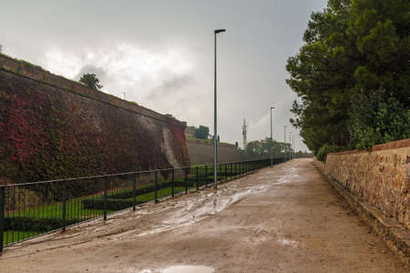 Perspective view of the foopath and walls of the Montjuic Castle in gloomy overcast day, Barcelona, Spainのeditorial素材