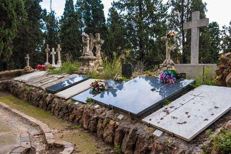 Several graves with gravestones and crosses on the Montjuic Cemetery in overcast day, Barcelona,...