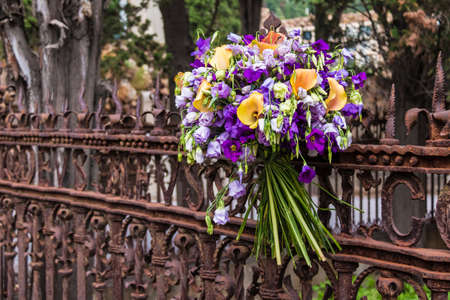 A bouquet of flowers on the wrought openwork fence on the Montjuic Cemetery closeup, Barcelona, Catalonia, Spainの写真素材