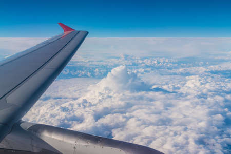 The wing of the airplane above the clouds closeup, view from the portholeの写真素材