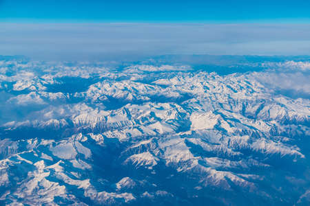 View from the porthole of airplane of a beautiful mountain landscapeの写真素材
