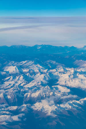 View from the porthole of airplane of a beautiful mountain landscapeの写真素材