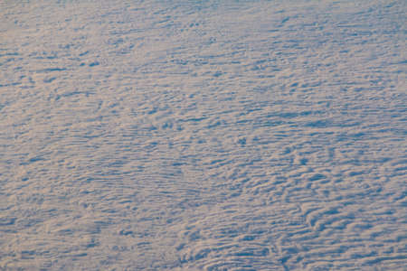 View from the porthole of airplane of a beautiful cloudscape at sunset