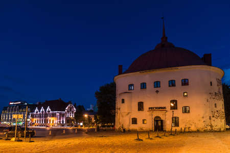 Vyborg, Leningrad Oblast, Russia - September 12, 2018: Beautiful view of the illuminated Market Square and the Round Tower at duskのeditorial素材