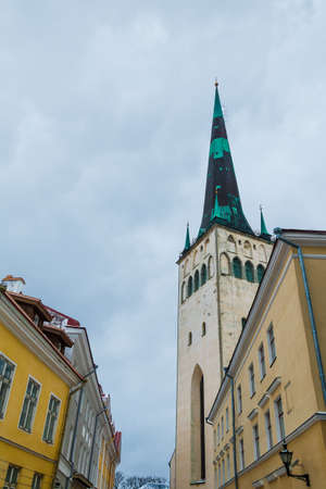Low-angle view of apartment buildings and the tower of the Saint Olaf's Church in overcast winter day, Tallinn Old Town, Estoniaの写真素材