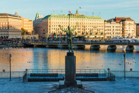 Stockholm, Sweden - December 26, 2018: The Sun Singer Memorial to Esaias Tegner on the background of the Strombron Bridge and historic buildings on embankment of the Norrstrom River in sunny winter dayのeditorial素材