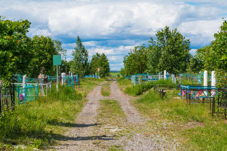 Perspective view of a track between graves in the Zaykovskoye Cemetery in sunny summer day, Kurgan, Russiaの写真素材