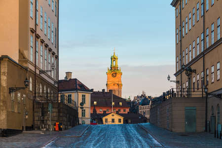 Perspective view of the Wrangelska Backen Street with historic buildings and the tower of the Saint Nicholas Church in the distance in winter day at sunset, Stockholm, Swedenの写真素材