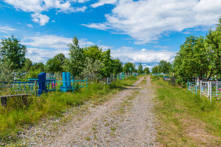 Perspective view of a track between graves in the Zaykovskoye Cemetery in sunny summer day, Kurgan, Russiaの写真素材