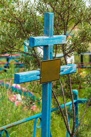 A grave cross with nameplate closeup in the Zaykovskoye Cemetery in sunny summer day, Kurgan, Russiaの写真素材