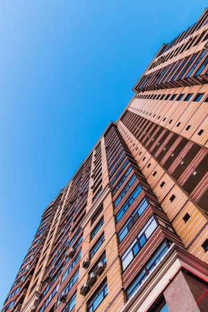Worm's-eye view of high-rise apartment building on the background of clear sky, Tyumen, Russiaの写真素材