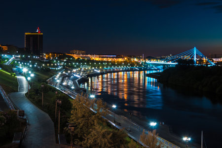 Beautiful view of the illuminated Embankment of Tura River and the Bridge of Lovers at dusk, Tyumen, Russiaの写真素材