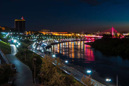 Beautiful view of the illuminated Embankment of Tura River and the Bridge of Lovers at dusk, Tyumen, Russiaの写真素材