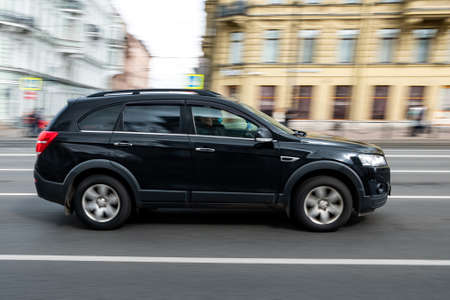 Side view of a black suv driving on the street.の写真素材