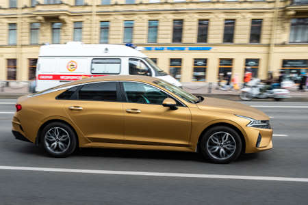 St. Petersburg, Russia, 03.05.2021: Gold kia cerato on the street road. Yellow kia. Blurred background. Car motion.のeditorial素材