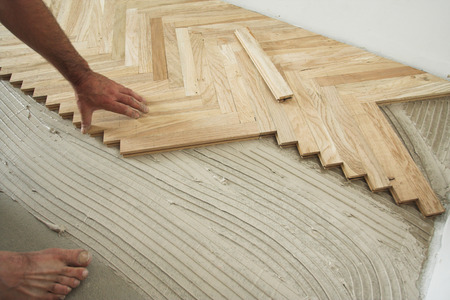 Carpenter on work putting wood floor - parquet pieces. Home construction conceptの写真素材