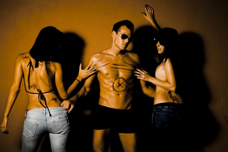 Portrait of jealous people. Handsome man in between two sexy womanの写真素材