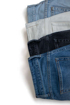 Isolate denim trousers of different textures and colors stacked on top of each other