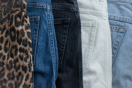 Denim trousers of different textures and colors stacked on top of each other