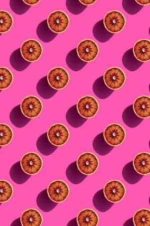 pattern of halves of red oranges on a pink background bright sunlight. High quality photoの写真素材