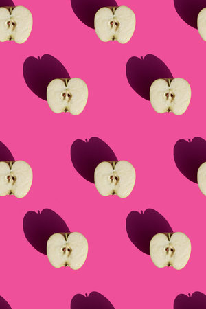 seamless pattern of halves of apples on a pink background with hard sunlight. High quality photoの写真素材