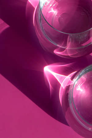 beautiful sun glare from glasses of water on a pink background, stylish layout for design. High...