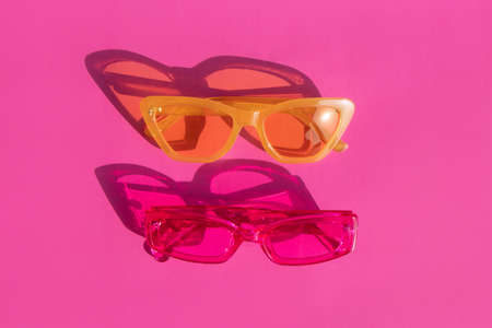 summer photo two sunglasses on a pink background top view beautiful shadows from bright sunlight. High quality photoの写真素材