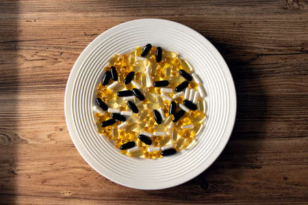 different vitamins and dietary supplements on a white plate, omega and vitamin d3