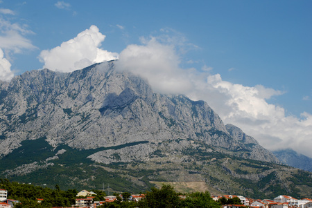 A small cloud on top of a mountain on a sunny dayの写真素材