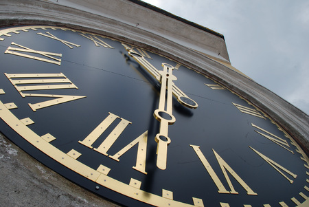 Clock face of the tower with golden hands and Roman numerals