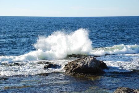 The high wave breaks on the rockの写真素材