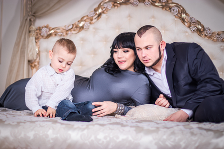 Dad and mom play with a son on the bed.の写真素材
