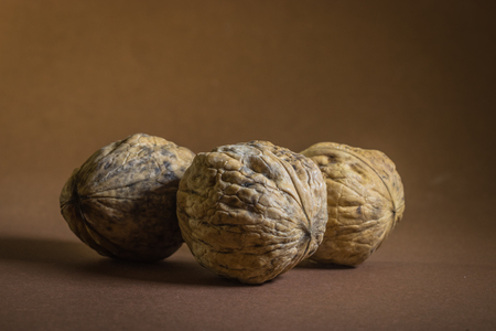 three Walnut walnuts on a dark brown background.の写真素材