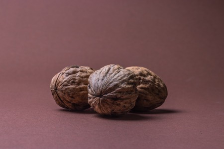 three Walnut walnuts on a dark brown background.の写真素材