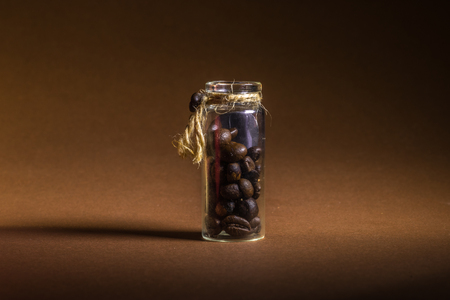 a small bottle with coffee beans on a brown background.の写真素材