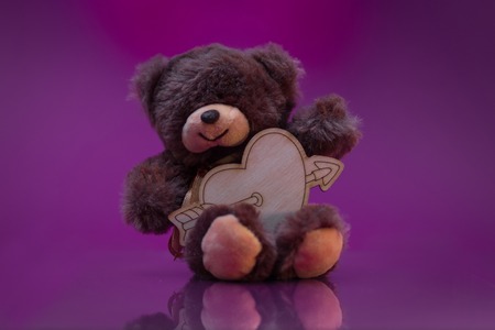 Teddy bear holding a heart and sits on the mirror surfaceの写真素材