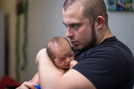Father holding and kissing newborn child with love.の写真素材