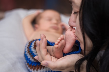 mom holding and kissing in the hands feet of newborn baby.の写真素材