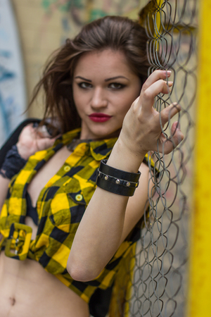 beautiful girl in Plaid Shirt standing by the fenceの写真素材