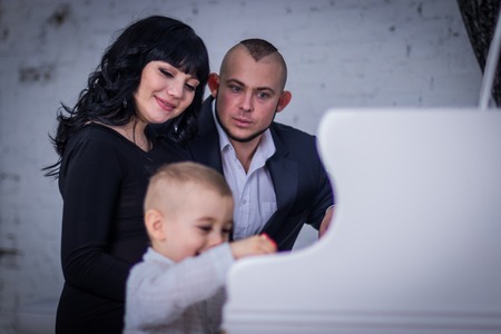 two-year old son plays the piano for mom and dadの写真素材