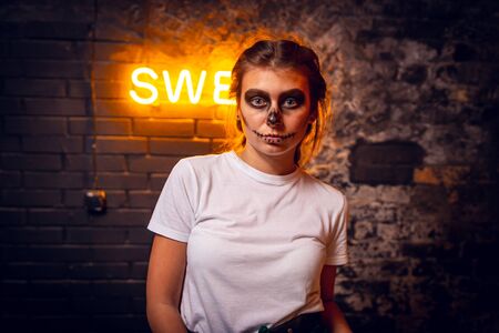 Portrait of young woman with scared halloween makeup over black backgroundの写真素材