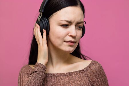 Image of a happy young beautiful woman posing isolated over pink wall background listening music...