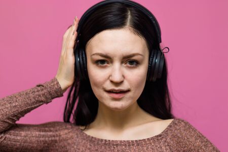 Image of a happy young beautiful woman posing isolated over pink wall background listening music with earphonesの写真素材