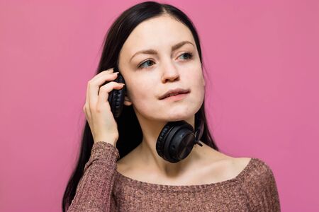 Image of a happy young beautiful woman posing isolated over pink wall background listening music with earphonesの写真素材
