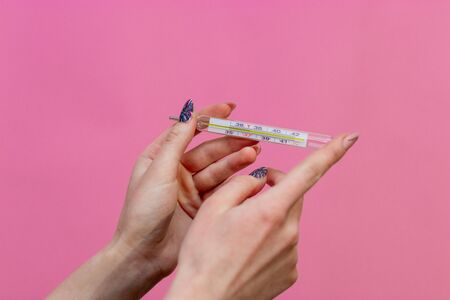 Closeup shot of Female hands holding a thermometer.の写真素材